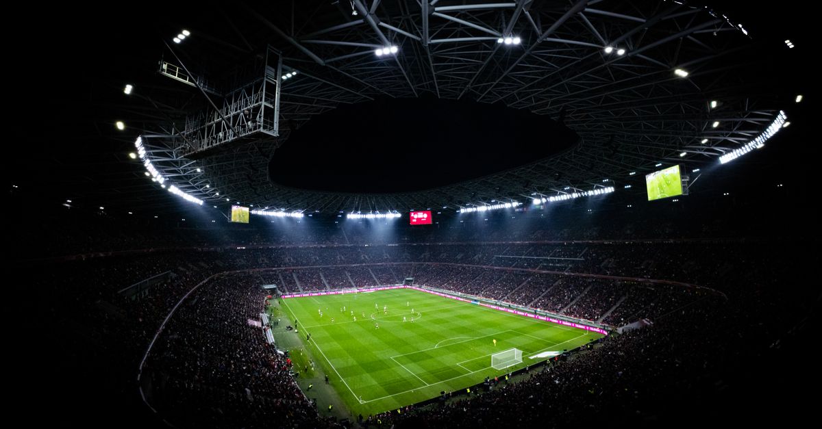 Aerial view of a night football match in an illuminated stadium.